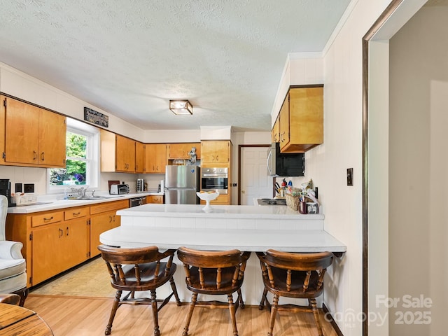85 Pine Ridge Rd, Mars Hill, NC 28754 - kitchen featuring stainless steel appliances, a peninsula, light countertops, a textured ceiling, and light wood-style flooring