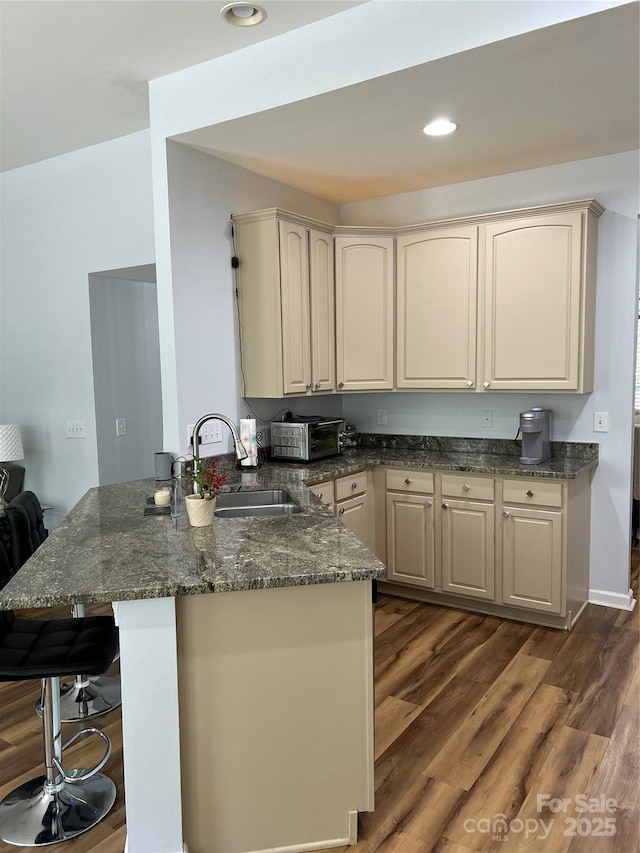 630 Springhouse Pl, Clover, SC 29710 - kitchen with a peninsula, a breakfast bar, wood finished floors, dark stone countertops, and recessed lighting
