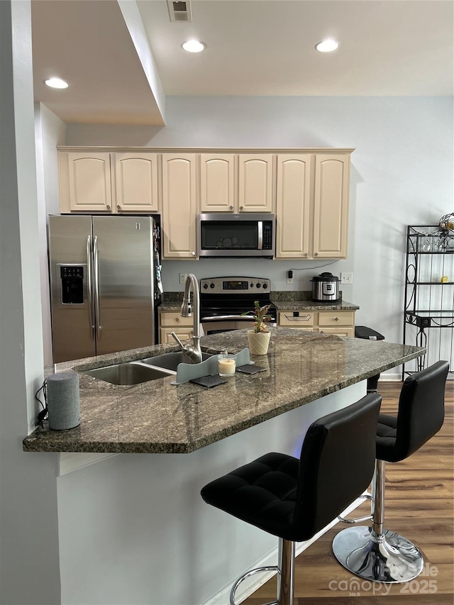 630 Springhouse Pl, Clover, SC 29710 - kitchen featuring appliances with stainless steel finishes, dark stone counters, wood finished floors, a kitchen breakfast bar, and recessed lighting