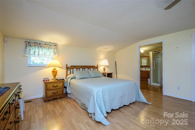 4720 Brevard Rd, Horse Shoe, NC 28742 - bedroom with light wood-type flooring, vaulted ceiling, a textured ceiling, and ensuite bathroom