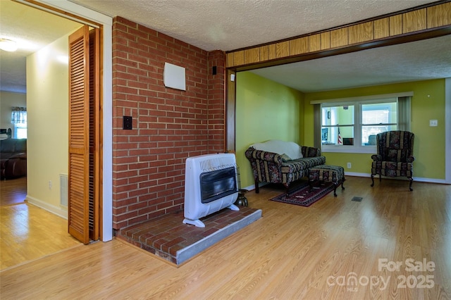 4720 Brevard Rd, Horse Shoe, NC 28742 - sitting room featuring heating unit, a textured ceiling, wood finished floors, a wood stove, and healthy amount of natural light