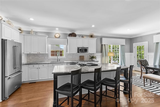 9012 Arrington Manor Pl, Charlotte, NC 28277 - kitchen with stainless steel appliances, a kitchen breakfast bar, white cabinets, light stone countertops, and decorative backsplash