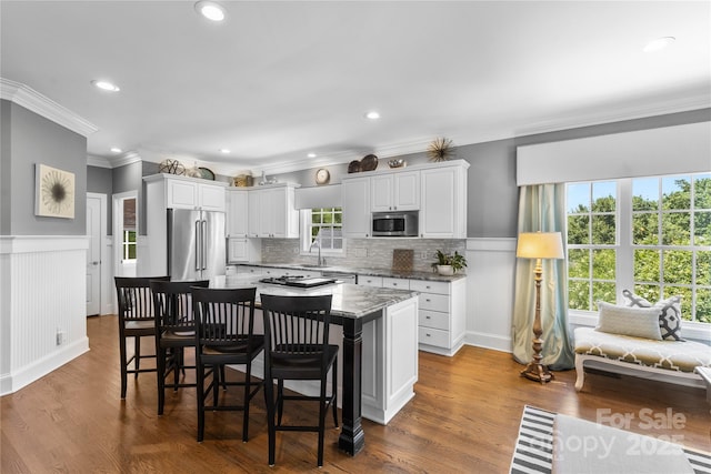 9012 Arrington Manor Pl, Charlotte, NC 28277 - kitchen with stainless steel appliances, crown molding, white cabinetry, a wainscoted wall, and a kitchen island