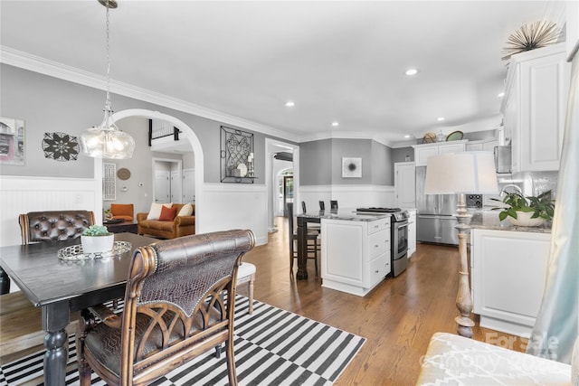 9012 Arrington Manor Pl, Charlotte, NC 28277 - dining area featuring arched walkways, crown molding, a wainscoted wall, recessed lighting, and dark wood-type flooring