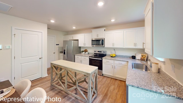 1053 20th Avenue Loop SE, Hickory, NC 28602 - kitchen with stainless steel appliances, light wood-style floors, white cabinetry, recessed lighting, and light stone counters