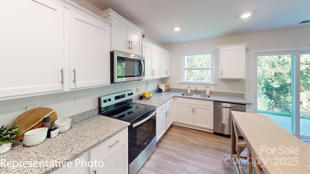 1053 20th Avenue Loop SE, Hickory, NC 28602 - kitchen with stainless steel appliances, white cabinetry, light wood-style flooring, recessed lighting, and light stone countertops