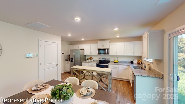 1053 20th Avenue Loop SE, Hickory, NC 28602 - kitchen with appliances with stainless steel finishes, light wood finished floors, white cabinetry, and recessed lighting