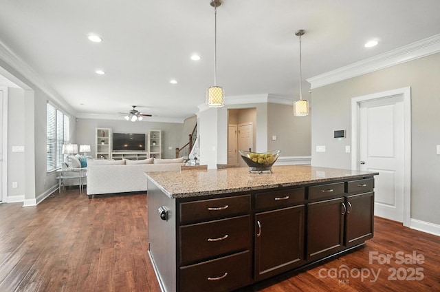 2006 Paddington Dr, Indian Trail, NC 28079 - kitchen with crown molding, ceiling fan, dark wood-style floors, light stone counters, and a kitchen island