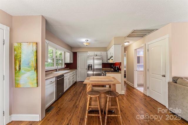 4 Northview Ln, Weaverville, NC 28787 - kitchen featuring stainless steel appliances, dark wood-type flooring, white cabinets, a textured ceiling, and under cabinet range hood