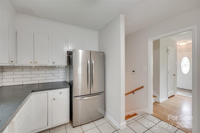 810 Applegate Ct, Gastonia, NC 28054 - kitchen with freestanding refrigerator, dark countertops, white cabinetry, decorative backsplash, and crown molding