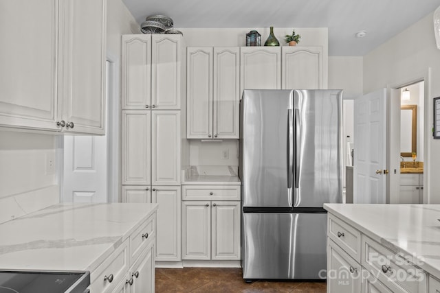 4108 Deerfield Dr NW, Concord, NC 28027 - kitchen with freestanding refrigerator, light stone counters, white cabinetry, and dark tile patterned flooring