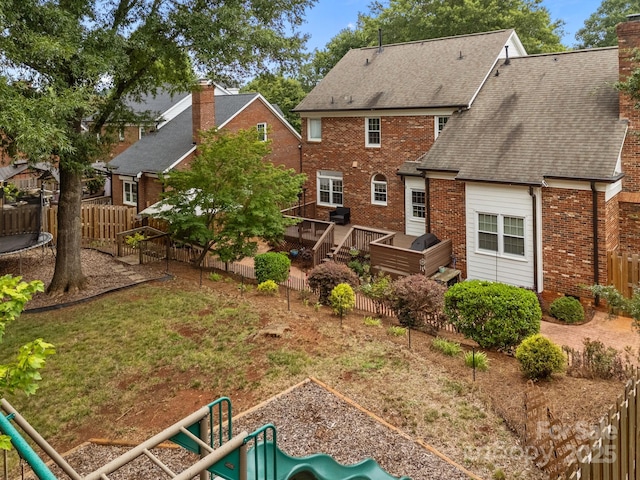 4108 Deerfield Dr NW, Concord, NC 28027 - back of house featuring a playground, a trampoline, brick siding, a chimney, and a fenced backyard