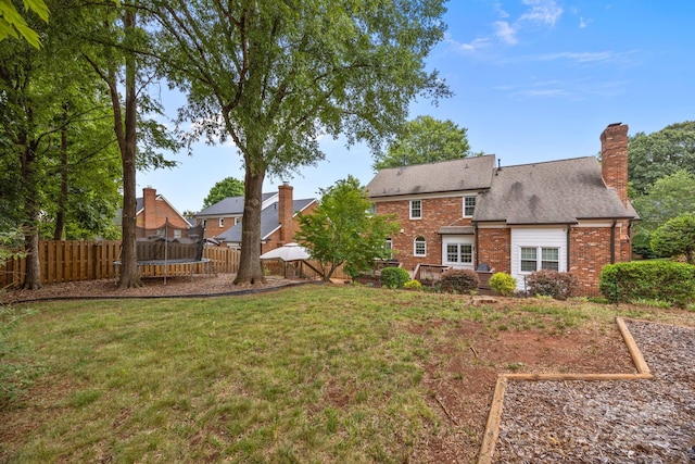 4108 Deerfield Dr NW, Concord, NC 28027 - back of property featuring a trampoline, brick siding, and a fenced backyard