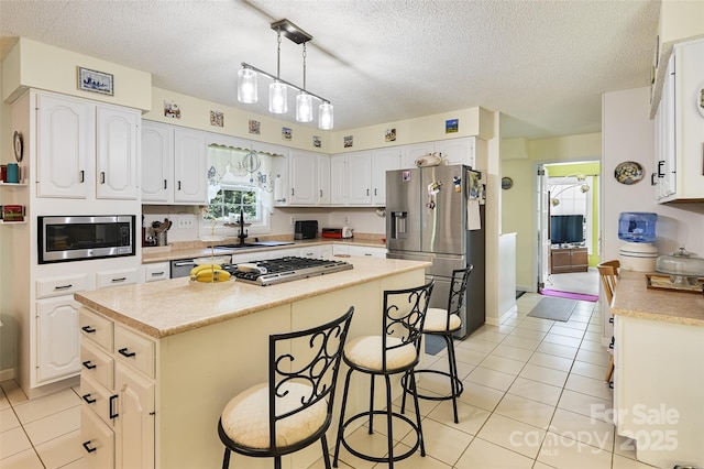 209 Camellia Way, Hendersonville, NC 28739 - kitchen featuring appliances with stainless steel finishes, light tile patterned floors, a textured ceiling, a breakfast bar, and a center island
