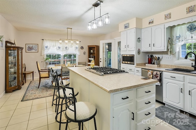 209 Camellia Way, Hendersonville, NC 28739 - kitchen featuring stainless steel appliances, a kitchen island, a textured ceiling, light tile patterned floors, and a breakfast bar