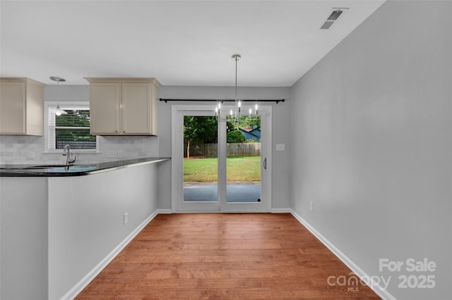 1940 Tyvola Rd, Charlotte, NC 28210 - kitchen featuring light wood-style floors, backsplash, decorative light fixtures, dark countertops, and a chandelier
