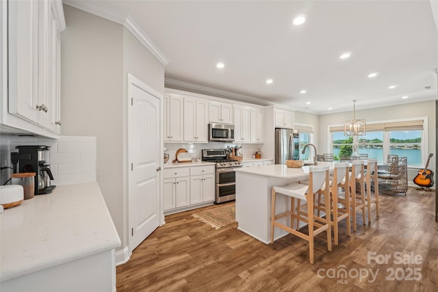 347 Landing Trl, Mount Gilead, NC 27306 - kitchen featuring appliances with stainless steel finishes, ornamental molding, light wood finished floors, decorative backsplash, and white cabinetry