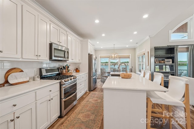 347 Landing Trl, Mount Gilead, NC 27306 - kitchen featuring stainless steel appliances, a kitchen bar, a kitchen island with sink, light wood finished floors, and decorative backsplash