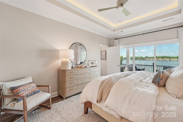 347 Landing Trl, Mount Gilead, NC 27306 - bedroom featuring access to exterior, a tray ceiling, a water view, wood finished floors, and a ceiling fan