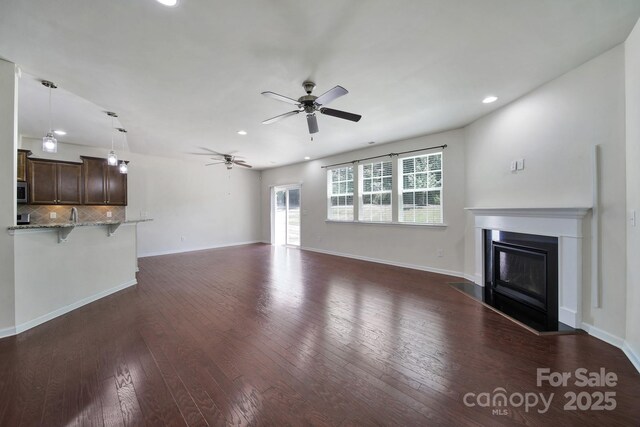 10328 Ebbets Rd, Charlotte, NC 28273 - unfurnished living room featuring ceiling fan, recessed lighting, a glass covered fireplace, and dark wood-type flooring