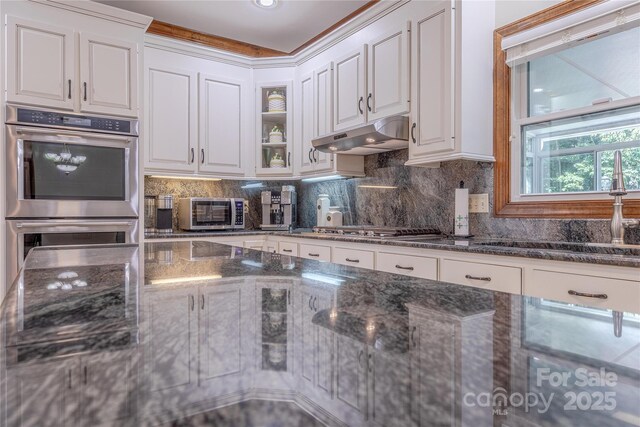 3100 Shady Grove Ln, Matthews, NC 28104 - kitchen with appliances with stainless steel finishes, white cabinets, under cabinet range hood, and dark stone counters