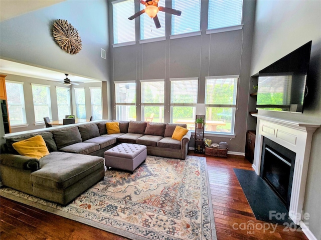 10302 Newbridge Rd, Charlotte, NC 28278 - living room featuring a ceiling fan, a towering ceiling, dark wood-style flooring, and a fireplace with flush hearth