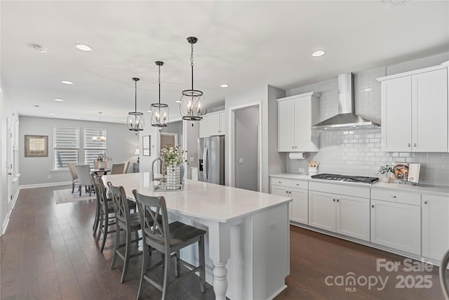 2225 Masons Bend Dr, Fort Mill, SC 29708 - kitchen featuring wall chimney range hood, stainless steel appliances, tasteful backsplash, light countertops, and an island with sink