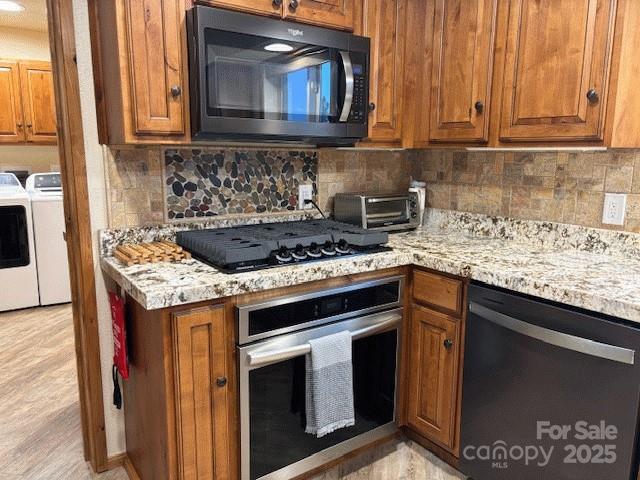 535 Lafayette Pl, Carthage, NC 28327 - kitchen featuring black appliances, washer and dryer, brown cabinets, and backsplash