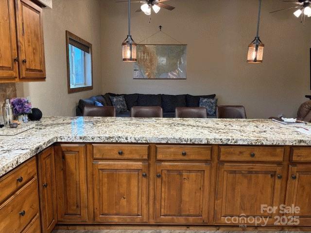535 Lafayette Pl, Carthage, NC 28327 - kitchen featuring a ceiling fan, brown cabinets, and light stone countertops