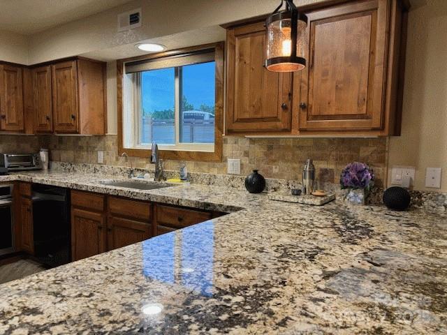 535 Lafayette Pl, Carthage, NC 28327 - kitchen featuring black dishwasher, light stone counters, brown cabinetry, and backsplash