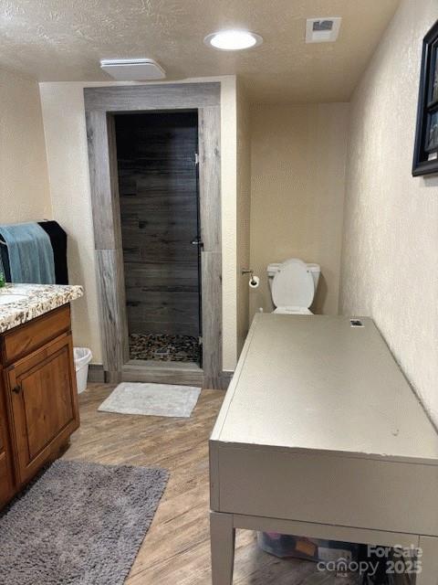 535 Lafayette Pl, Carthage, NC 28327 - full bath with vanity, wood finished floors, a stall shower, a textured ceiling, and a textured wall