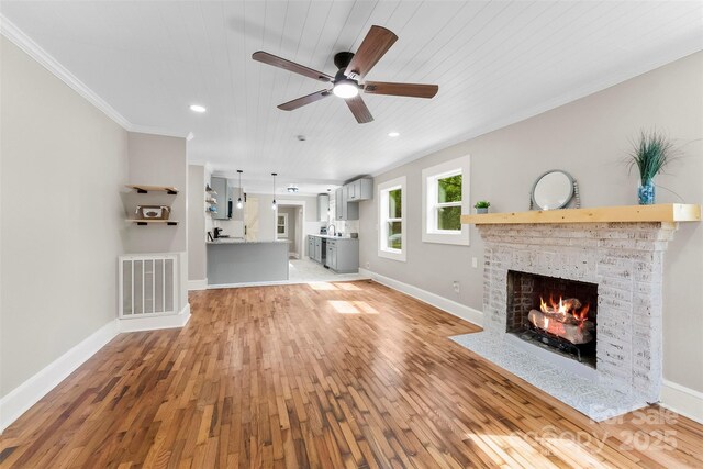 410 Gann St, Lowell, NC 28098 - unfurnished living room with a brick fireplace, light wood-style floors, a ceiling fan, ornamental molding, and wood ceiling