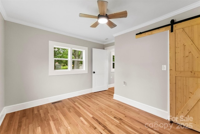 410 Gann St, Lowell, NC 28098 - unfurnished bedroom featuring light wood-style flooring, crown molding, a barn door, and ceiling fan
