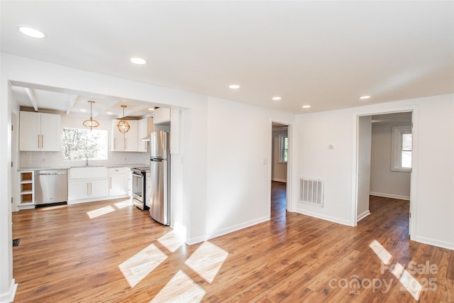 678 Wagner St, Troutman, NC 28166 - kitchen with appliances with stainless steel finishes, white cabinets, light countertops, open floor plan, and light wood-style floors