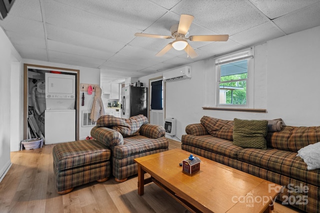 306 Forest Ave, Franklin, NC 28734 - living room featuring estacked washer and dryer, a paneled ceiling, light wood-style floors, heating unit, and a wall unit AC