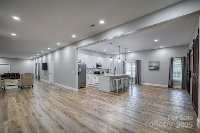 2545 10th Street Ct NE, Hickory, NC 28601 - kitchen with appliances with stainless steel finishes, open floor plan, a barn door, white cabinetry, and light wood-style flooring