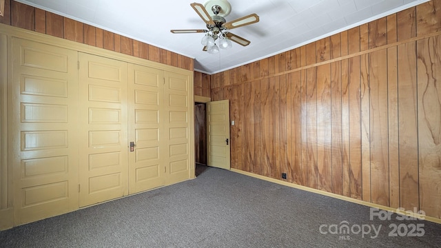 221 Kings Mountain St, Clover, SC 29710 - unfurnished bedroom with carpet floors, wood walls, a closet, and a ceiling fan