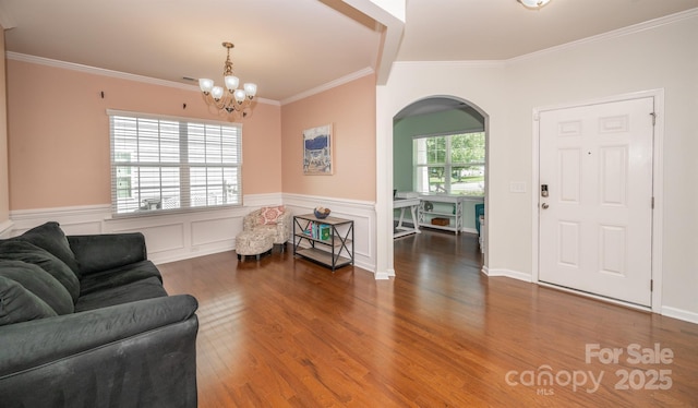 10666 Sapphire Trl, Davidson, NC 28036 - living room with arched walkways, a chandelier, crown molding, wood finished floors, and wainscoting