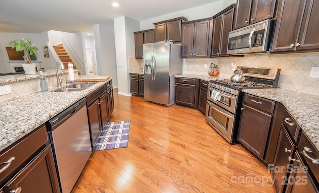10666 Sapphire Trl, Davidson, NC 28036 - kitchen with appliances with stainless steel finishes, light wood-style floors, dark brown cabinets, decorative backsplash, and recessed lighting