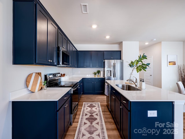 2511 Ruby Dixon Crossing Dr Unit 23, Gastonia, NC 28056 - kitchen featuring stainless steel appliances, light wood-type flooring, a center island with sink, blue cabinetry, and recessed lighting