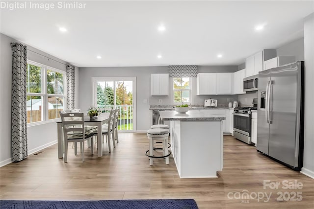 5925 Granbury Dr, Kannapolis, NC 28081 - kitchen with stainless steel appliances, a center island, recessed lighting, white cabinetry, and a kitchen bar