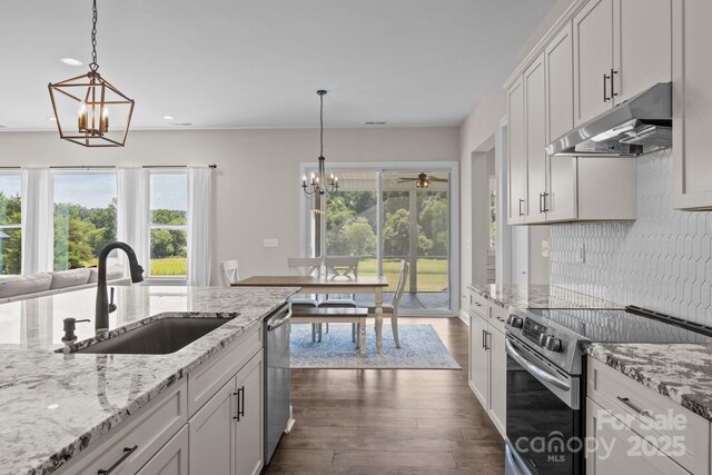 1140 Shinnville Rd, Cleveland, NC 27013 - kitchen featuring appliances with stainless steel finishes, under cabinet range hood, a chandelier, dark wood finished floors, and backsplash