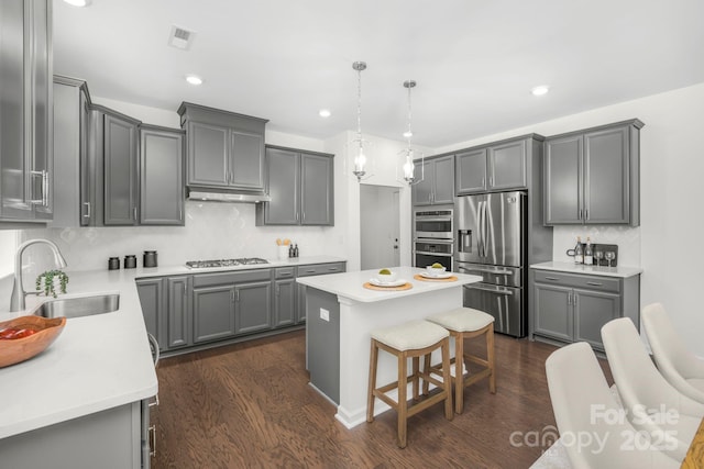 17203 Summers Walk Blvd, Davidson, NC 28036 - kitchen with stainless steel appliances, decorative backsplash, gray cabinets, dark wood-style floors, and a center island