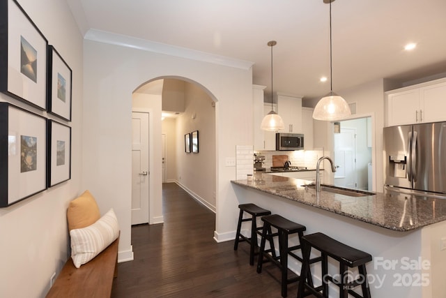 5907 Barrowlands Ct, Charlotte, NC 28210 - kitchen featuring appliances with stainless steel finishes, arched walkways, a breakfast bar, dark stone countertops, and recessed lighting