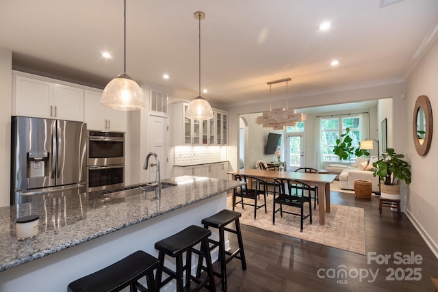 5907 Barrowlands Ct, Charlotte, NC 28210 - kitchen with stainless steel appliances, white cabinets, recessed lighting, a breakfast bar area, and backsplash