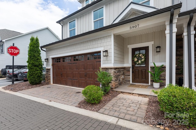 5907 Barrowlands Ct, Charlotte, NC 28210 - property entrance featuring board and batten siding, stone siding, a garage, and decorative driveway