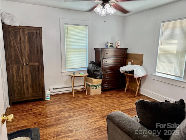 703 Stage St NW, Lenoir, NC 28645 - living area with a baseboard heating unit, wood finished floors, ceiling fan, and plenty of natural light