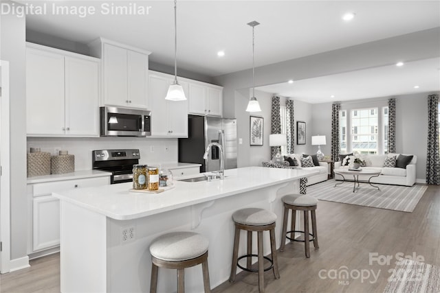 1348 Holden Ave SW, Concord, NC 28025 - kitchen with appliances with stainless steel finishes, open floor plan, white cabinets, an island with sink, and a breakfast bar