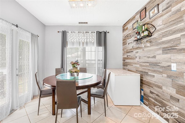 9910 Sandman Ln, Charlotte, NC 28216 - dining space with wooden walls, an accent wall, and light tile patterned floors