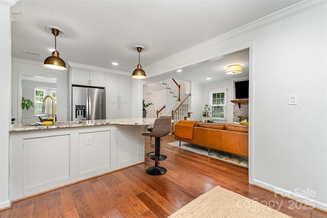 3106 Windstream Ct, Charlotte, NC 28210 - kitchen with stainless steel fridge with ice dispenser, crown molding, wood finished floors, light stone countertops, and decorative light fixtures